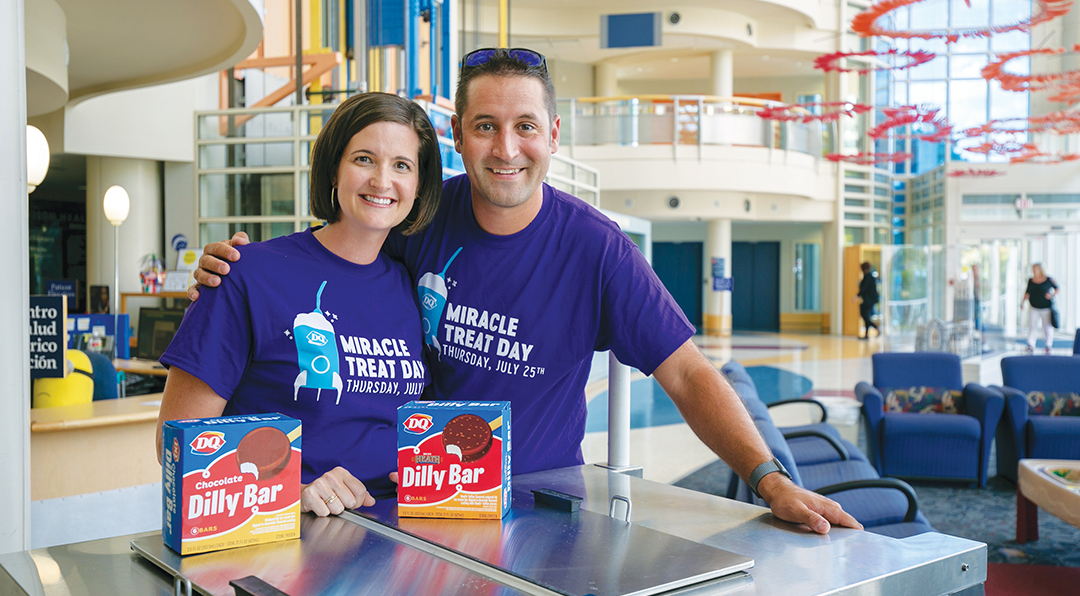 A couple wearing purple shirts pose with ice cream