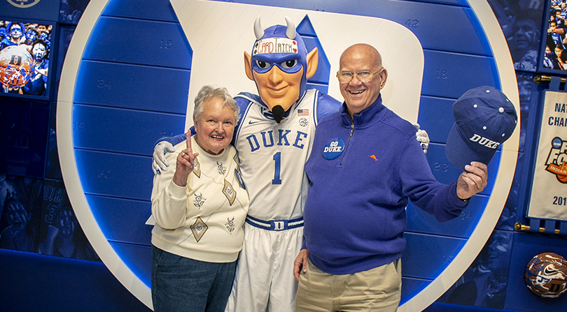 An elderly couple poses with the Duke Blue Devil