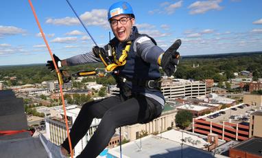 A young man rappels off of the rooftop of 21c Museum Hotel in downtown Durham on a beautiful fall day.