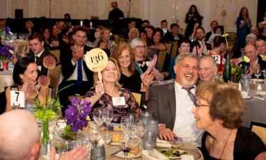 A party and a woman raising an auction paddle