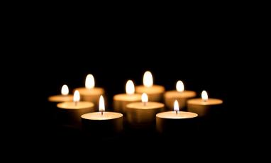 A bunch of lit votive candles in a black background.
