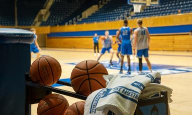 Duke Men's Basketball Players in the background, basketballs in the foreground, Cameron Indoor at the location.