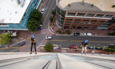 Two individuals are seen from above, rappelling off the side of 21c Museum Hotel in downtown Durham. 