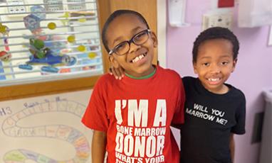 Two little boys standing next to each other with their arms around each other