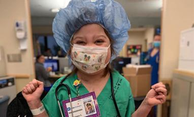 Little girl wearing scrubs and a mask as a surgeon would wear going into surgery
