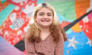 A photo of Samantha, a 10-year-old white girl with multicolored hair and a big smile.