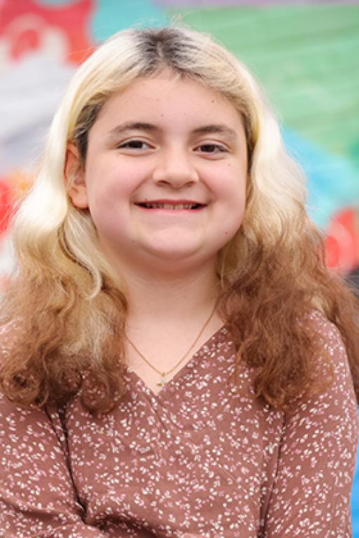 A photo of Samantha, a 10-year-old white girl with multicolored hair and a big smile. 