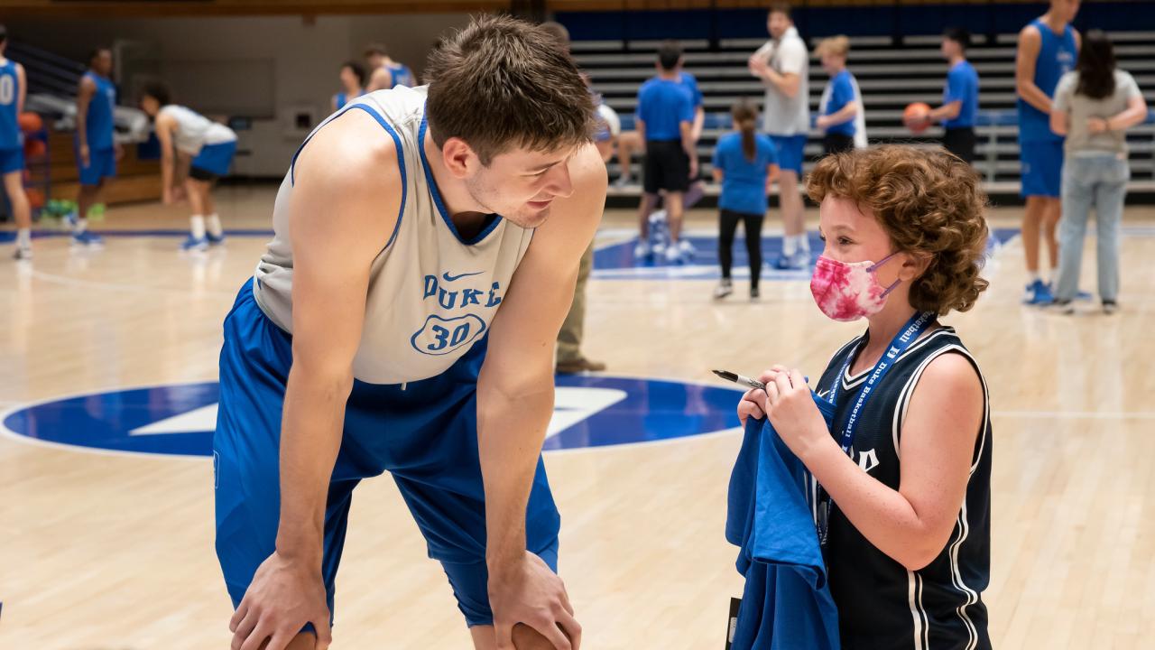 A Duke Men's Basketball player talks to a Duke Children's patient 